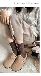 Detail of cable knit wool socks paired with warm shearling lined mule shoes and midi skirt