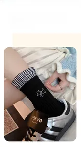 Detail of embroidered puppy on black knit mid-calf socks with checkered ruffled cuffs