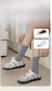 Close-up of grey wool socks with blue polka dots and ruffle edges on feet