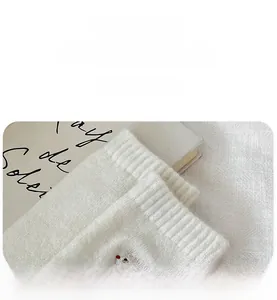 Detail of ribbed cuff on white wool socks with cute bear embroidery and elastic texture