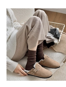 Close-up of light brown suede mules with warm fur lining and thick knit socks