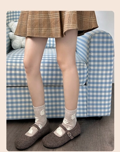 Detail of light brown crew socks with white rabbit patterns paired with wool Mary Janes