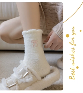 Close-up of white thermal socks featuring pink bow embroidery and ruffled edges detail