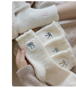 Detail of soft white thermal socks featuring delicate bow embroidery and plush texture