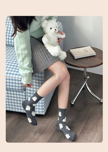 Detail of grey crew socks with white cartoon sheep pattern and ribbed knit cuffs