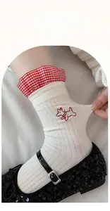 Detail of white cotton socks with red plaid ruffled cuff and cute dog embroidery