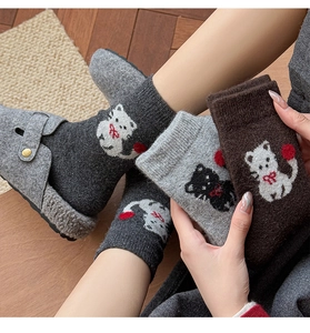 Detail von warmen Winter-Katzen-Socken mit weißem Kätzchenmuster und rotem Pompon