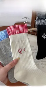 Close-up of cotton socks featuring plaid ruffle trim and cute dog embroidery detail