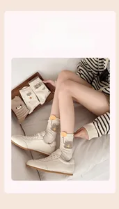 Detailansicht von süßen Bären-Flockprints auf cremeweißen Socken mit bunten Farbtupfern