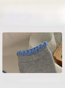 Detail view of elastic blue wavy cuff on gray wool socks with cozy home background