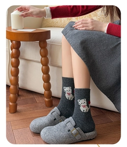 Detail von dunkelgrauen Wollsocken mit weißem Katzen-Jacquard und roter Schleife