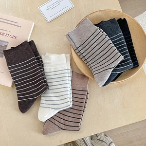 Striped wool blend mid-calf socks in various colors displayed on a wooden surface