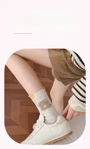 Nahaufnahme der weißen gepunkteten Socken mit Bären-Stickerei und gelben 3D-Ohren