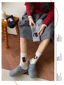 Detail von süßen Katzensocken mit rotem Pompon am Schwanz in gemütlicher Atmosphäre