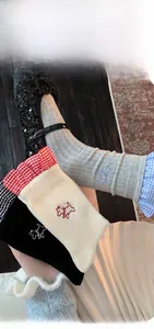 Detail of cute embroidered puppy socks with red plaid lace trim in grey black and beige