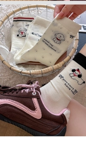 Close-up of white crew socks with cartoon dog prints and black letter embroidery