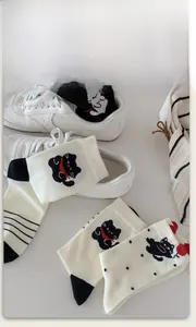 Detailed view of high-quality cotton socks with cute cartoon cat patterns and red bow ties