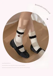 Detail of cream crew socks with cat embroidery, frill cuffs, and black Mary Jane shoes