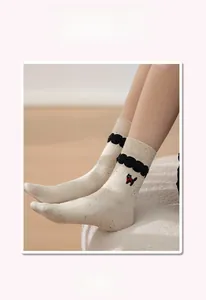 Detail of cartoon cat embroidery and ruffled cuff on cream speckled crew socks