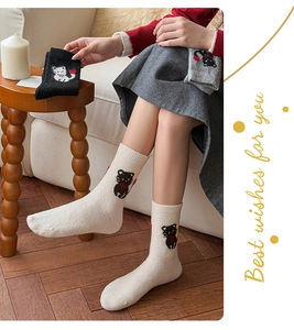 Detailansicht süßes Katzenmuster mit roter Schleife auf dicken warmen Winterstricksocken