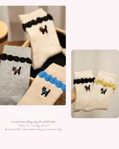 Close-up of cat embroidery and ruffled cuffs on colorful speckled crew socks