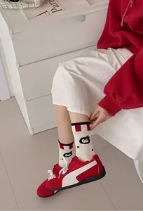 Detail of cute penguin embroidery and red striped cuffs on white cotton mid-calf socks