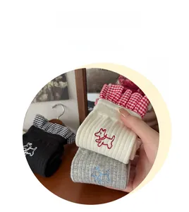 Detail of embroidered puppy on ribbed socks with plaid ruffle trim and knitted texture
