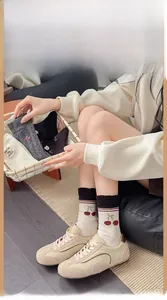 Close-up of wool socks featuring embroidered cherry patterns and stripe details