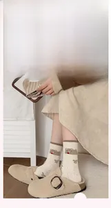 Detail von cremeweißen Socken mit braunem Bären und Schleife am Model getragen