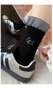 Detail of black crew socks with white puppy embroidery and checkered ruffle edges