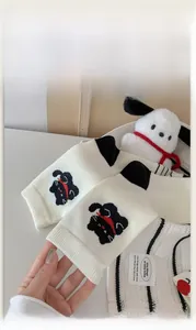 Close-up of white knitted cotton socks featuring cute cartoon dog embroidery and details