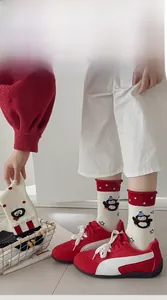 Detail view of cotton mid-calf socks with red penguin motifs and polka dot cuffs