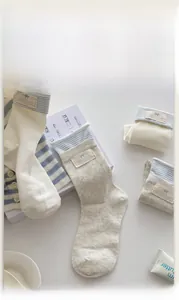 Close-up of ribbed knit socks in cream and grey with blue striped cuff and tag detail
