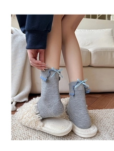 Detail of grey ribbed knit socks featuring blue ruffled edges and delicate ribbon bows