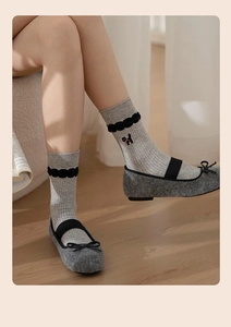 Close-up of grey knit crew socks with cat embroidery and lace trim on Mary Jane shoes