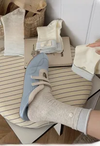 Detail of blue striped knit socks with button labels and blue ballet flats on a stool