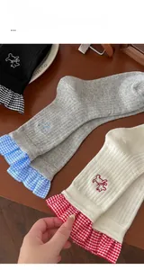 Macro shot of cotton socks featuring dog embroidery and gingham lace trim on wooden background