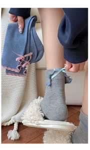 Detail of blue and grey ribbed cotton socks with bow and ruffled cuff trim