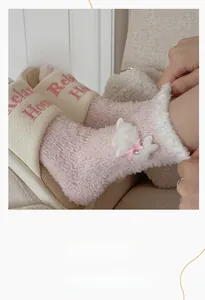 Detail of pink coral fleece socks featuring a cute plush bunny with silk ribbon and bell