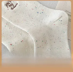 Close-up of cream wool blend socks with colorful flecks and embroidered cuffs