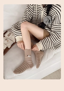 Detail der süßen Bärenstickerei auf braun gestreiften Socken für Herbst und Winter