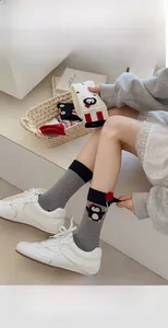 Close-up of cute cartoon penguin socks in gray cotton blend with red fuzzy ball detail