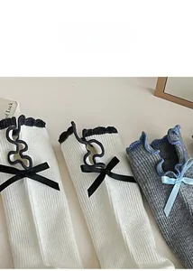 Detailed view of women's ribbed knit socks featuring ruffle edges and satin bow ties