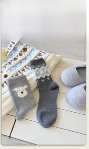 Detail of gray knitted socks featuring cute puppy and snowflake patterns for winter comfort