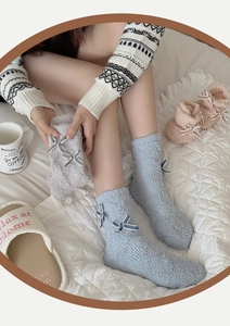 Detailstruktur dicker Korallenfleece-Socken mit süßen weißen Doppelschleifen-Akzenten