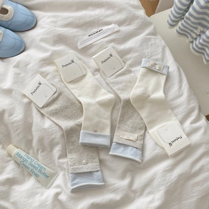 Blue-gray striped mid-calf socks set with button and fabric label on white bedding