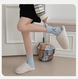 Detail von hellblauen Korallenvlies-Socken mit Schleife und flauschigen weißen Hausschuhen