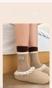Dettaglio di calze in maglia Fair Isle con toppa Goodluck e pantofole con bordo in pizzo