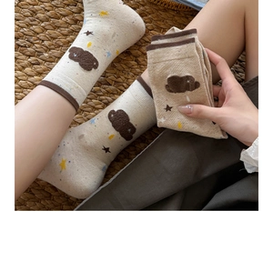 Detail of warm beige crew socks with brown cloud flocking and colorful star patterns