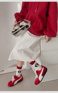 Detail of white cotton penguin socks with red polka dot cuffs paired with sneakers